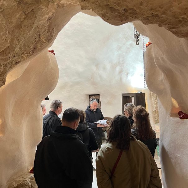 Gruppo di persone in visita presso il frantoio rosso ipogeo con giuseppe, il titolare, che fa da guida