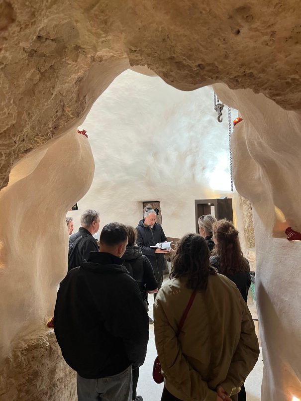 Gruppo di persone in visita presso il frantoio rosso ipogeo con giuseppe, il titolare, che fa da guida