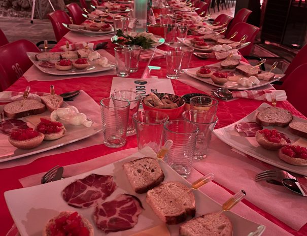 Tavolata presso frantoio rosso ipogeo con una luce soffusa rossa, prodotti tipici della valle d'itria tra cui: pane tipico condito con olio , capocollo di martina franca, mozzarella e formaggi, bruschette